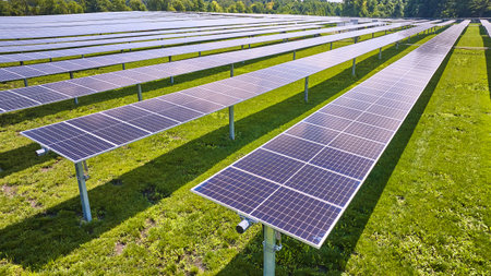 Close up solar panels fading into long rows in aerial over farm