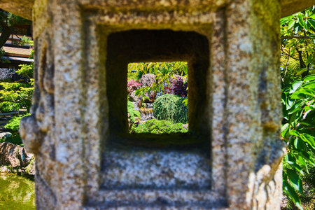 View of garden with mini waterfall seen through Japanese stone lanternの写真素材