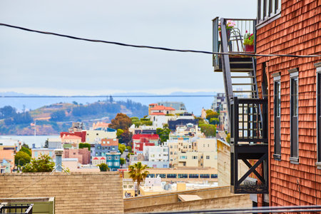 Side of reddish brown building with black stairs and patio overlooking city buildings in Californiaの写真素材