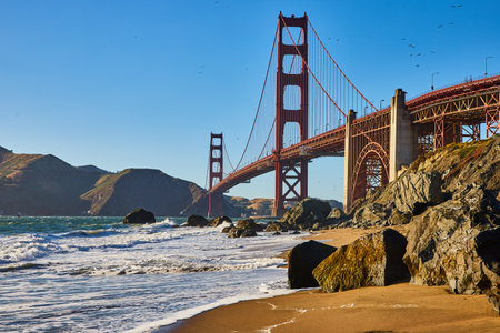 Boulders on sandy beach with waves and close view of Golden Gate Bridgeの写真素材