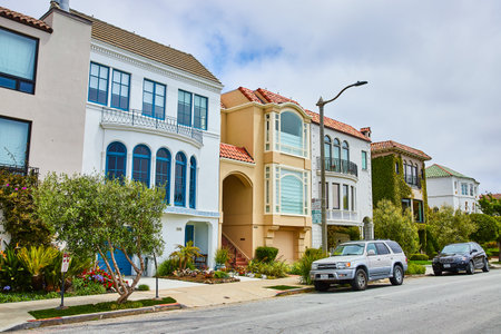 Side by side houses with varying pastel colors on street under overcast sky in Marina Districtの写真素材