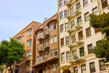 Close together apartment buildings with fire escapes in San Francisco with earthy color tonesの写真素材