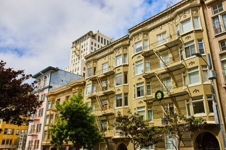 Pale yellow apartment buildings close together connected by fire escapesの写真素材