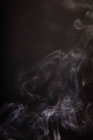 Graceful Incense Smoke Swirls Against Dark Backgroundの写真素材