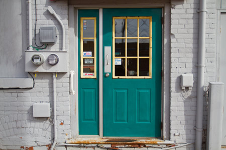 Teal Door with Yellow Framed Glass in White Brick Building Entrance