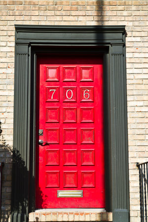 Metallic Number on Vibrant Red Door with Brick Wall in Daylightの写真素材