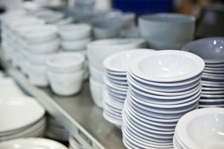 Commercial Kitchen Ceramic Dishware Stacked on Metallic Shelvesの写真素材