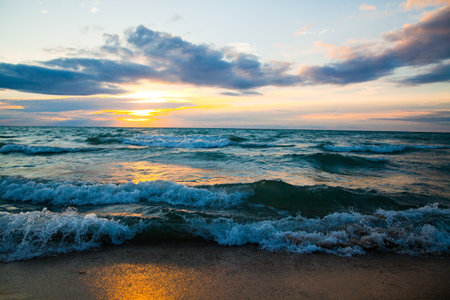 Tranquil Sunset Over Lake Michigan with Rolling Waves and Golden Glowの写真素材