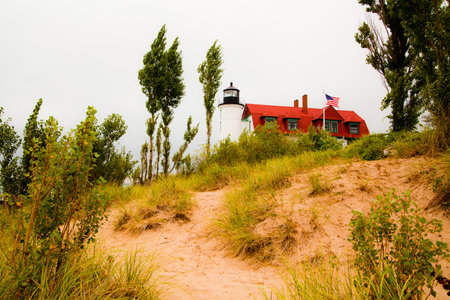 Classic Lighthouse and Red-Roofed House on Michigan Coastline Sand Dunesの写真素材