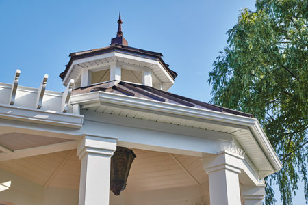 Traditional Home Roof Details and Weathervane Against Blue Skyの写真素材