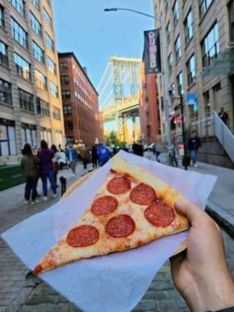 Hand-Held Pepperoni Pizza with DUMBO Bridge Backgroundの写真素材
