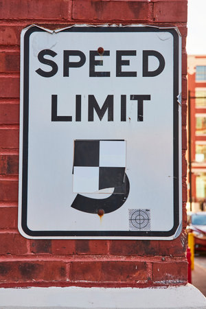 Defaced Urban Speed Limit Sign on Brick Wallの写真素材