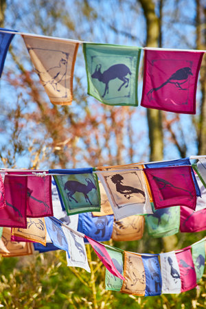 Colorful prayer flags with animal silhouettes flutter at Fort Wayne Zoo, symbolizing peace and...