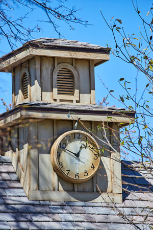 Vintage clock tower at Fort Wayne, framed by spring branches against a blue sky, embodying timeless charm.の写真素材
