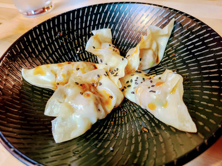 Elegant Dumplings with Sesame Seeds on Black Plate Eye-Level View