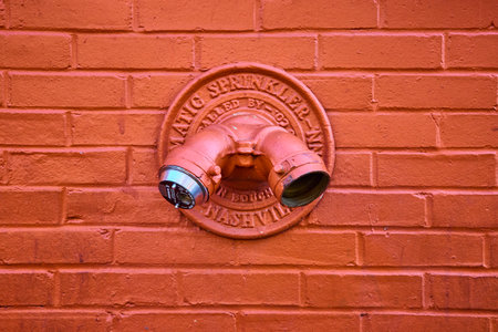 Orange Fire Department Connection on Brick Wall Close-Up