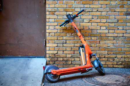 Abandoned Orange Scooter Against Yellow Brick Wall Eye-Level Perspectiveの写真素材