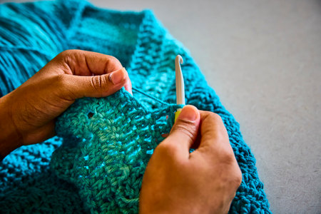 Hands Crocheting Blue Yarn Close-Up with Tattoo Detail