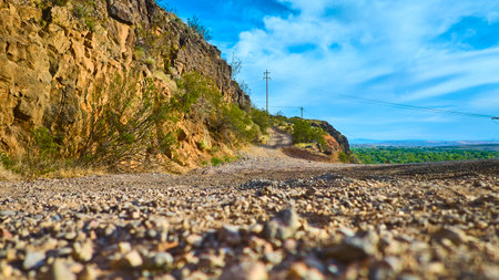 Desert Gravel Road and Rocky Cliff with Power Lines Ground Level Motionの写真素材
