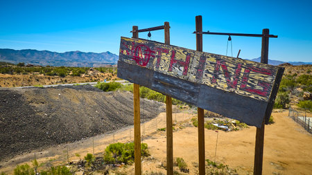 Aerial of Weathered Nothing Sign in Desert Landscape with Mountains