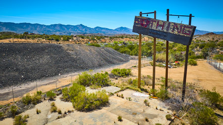 Aerial Abandoned Desert Roadside Sign and Empty Lot with Mountains Fly Overの写真素材