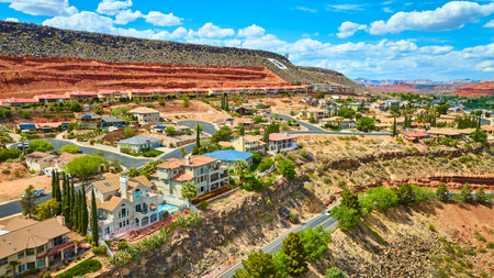 Aerial Suburban Homes and Red Rock Cliffs in Desert Landscape Fly Overの写真素材