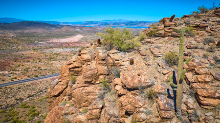 Aerial Fly Over Sonoran Desert Cliffs Saguaro Cacti and Highwayの写真素材