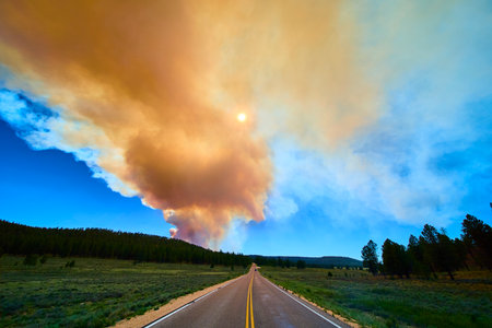 Wildfire Smoke Plume Over Scenic Road and Forest Under Sunlit Sky Utahの写真素材