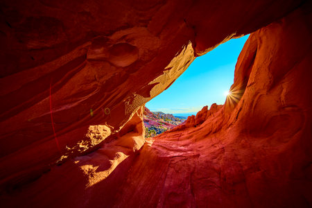 Sunburst Through Red Rock Arch Formation in Nevada Desert Canyonの写真素材