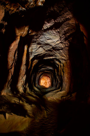 Rugged Rock Tunnel Interior with Warm Light and Graffiti Belly of the Dragon Caveの写真素材