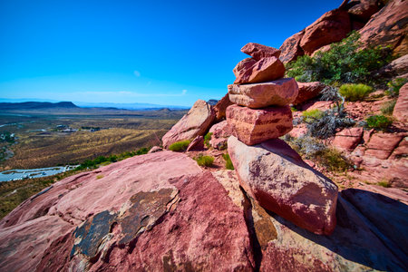Rock Stack Cairn on Red Rock Outcrop with Desert Valley and Blue Skyの写真素材