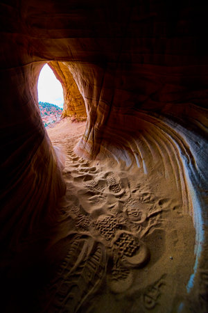 Sandstone Cave Interior with Footprints and Sunlit Desert Opening Kanab Utahの写真素材