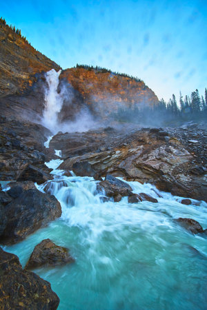 Takakkaw Falls Powerful Waterfall Cascading Over Rocky River in Mountain Landscapeの写真素材