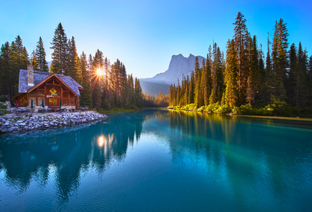 Sunrise Lodge Reflected in Tranquil Lake with Forest and Mountain View Golden Hourの写真素材