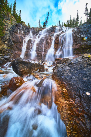 Tangle Falls Majestic Waterfall Flow Over Rocky Cliffs and Evergreen Forest