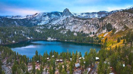 Aerial Mountain Lake and Snow Dusted Peaks Surrounded by Evergreen Forest