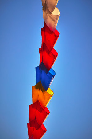 Colorful Kite Chain Against Blue Sky at Kite Festival