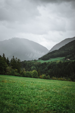 Majestic mountains in the Alps covered with trees and cloudsの写真素材