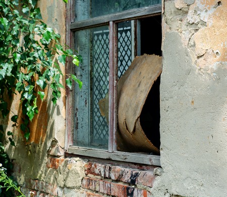A broken glass in the window closed with a piece of plate