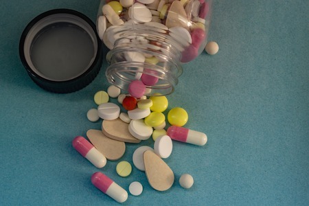 different pills from a bottle on a blue backgroundの写真素材