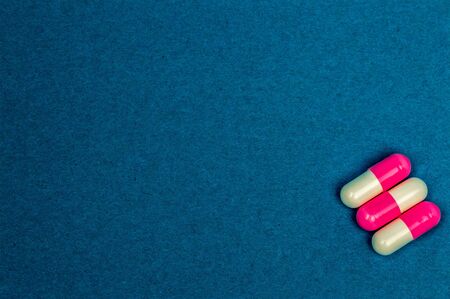 three red-and-white oval tablets on a blue background. Place for writing