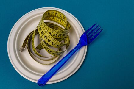 plastic blue fork, plastic plate, measuring tape blue background. closeupの写真素材