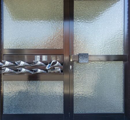 glass door with newspapers in mailboxes closeupの写真素材