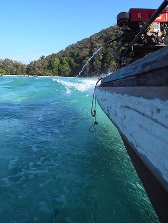 Wooden boat leaving with a bow wave.の写真素材