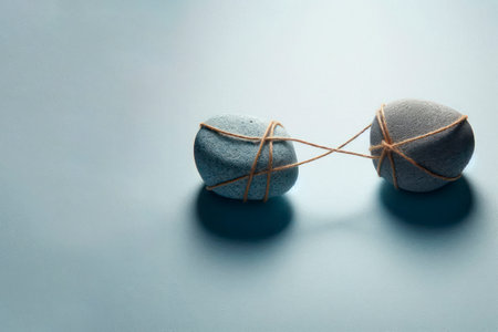Two rocks tied together with a rope on a clean background. Space for textの素材