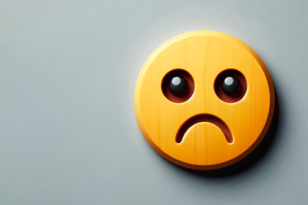 Wooden yellow emoji with a sad expression on a gray background. Space for textの素材
