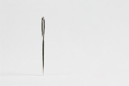Eye of a needle in macro photography on a white background. Space for textの素材