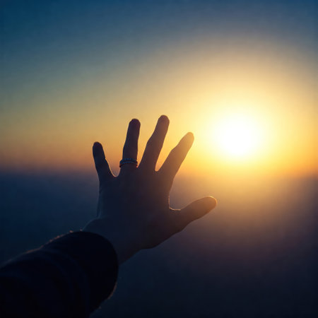 A hand reaches for the sun against the sunsetの素材