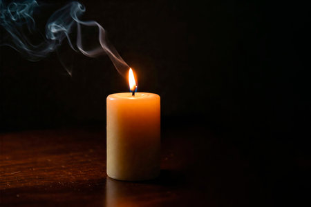 A burning candle in a dark room with clouds of smoke. Space for textの素材