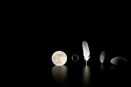 The moon, feathers, a soap bubble and a stone in the dark. Space for textの素材